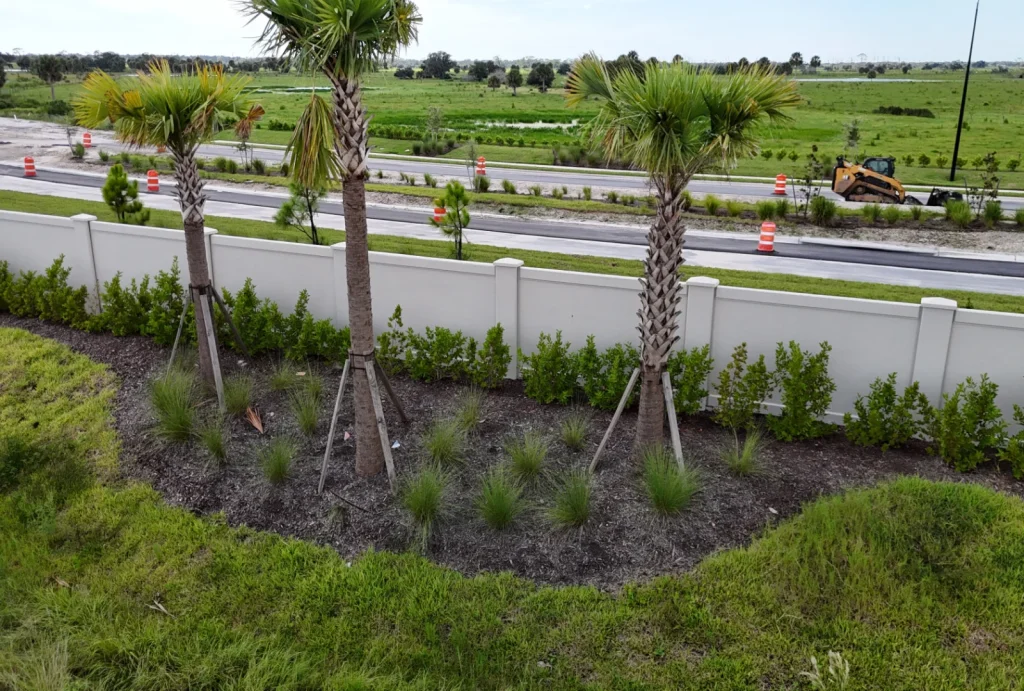 A capped-top Permacast precast concrete perimeter wall with landscaping and palms running along a roadway and open ground — representative of the clean, institutional-grade perimeter walls Permacast delivers for government, campus, and public-infrastructure projects across Tallahassee and Leon County
